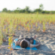 Woman laying on a yoga mat preparing for yoga Nidra in the sand,