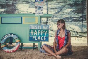 Girl sitting happily next to a sign that says "This is my happy place."